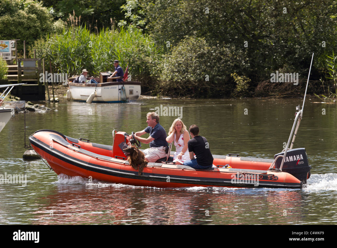 La nervatura speedboat con famiglia e cane crociera sul fiume al di sotto del limite di velocità Foto Stock