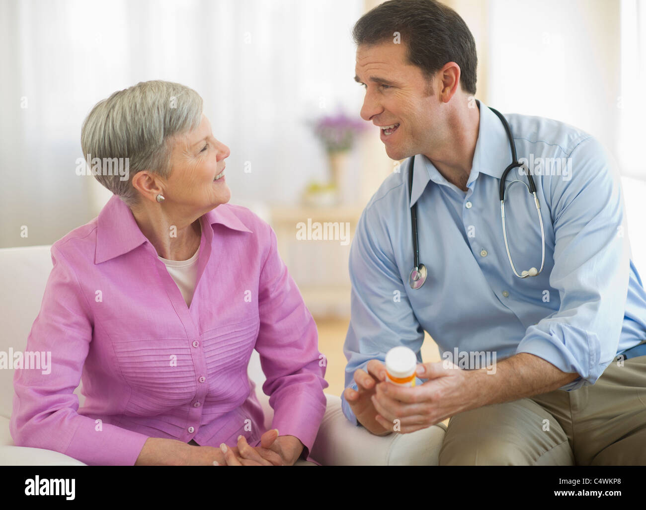Stati Uniti d'America,New Jersey,Jersey City,sorridente Medico medicina dando bottiglia alla donna senior Foto Stock
