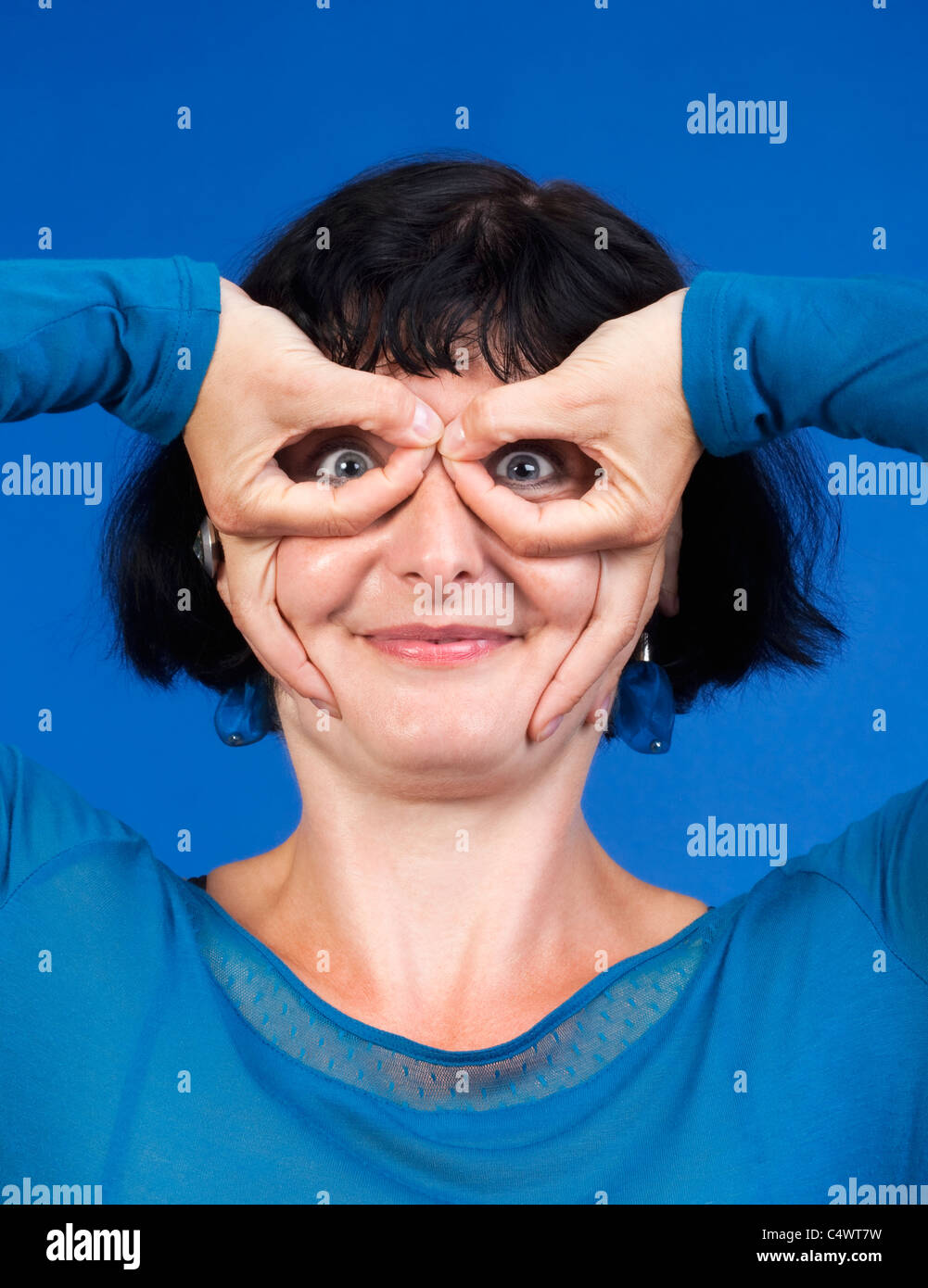 Donna di mezza età rendere divertente gesto - isolato su blu Foto Stock