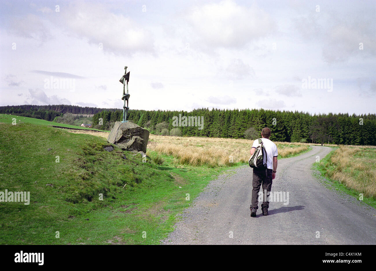 Rambler camminando lungo la strada a Glenkiln con figura permanente di scultura, Dumfries & Galloway, Scotland, Regno Unito. Modello rilasciato Foto Stock Rambler camminando lungo la strada a Glenkiln con figura permanente di scultura, Dumfries & Galloway, Scotland, Regno Unito. Modello rilasciato Foto Stock