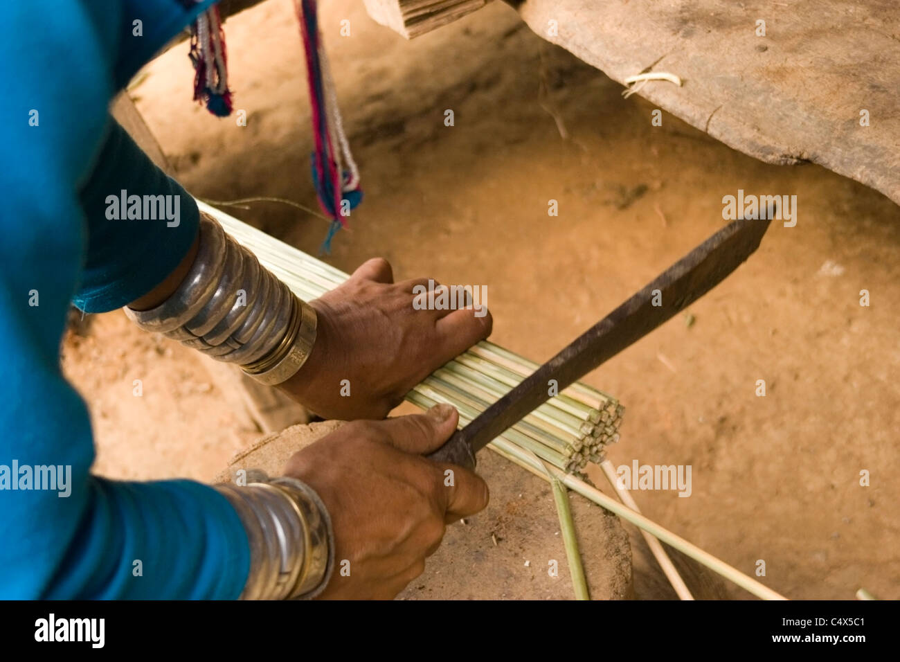 Un Karen Paduang donna dalla Birmania indossare anelli oro intorno al suo collo è rendere una scopa a casa sua in un campo di rifugiati in Thailandia. Foto Stock