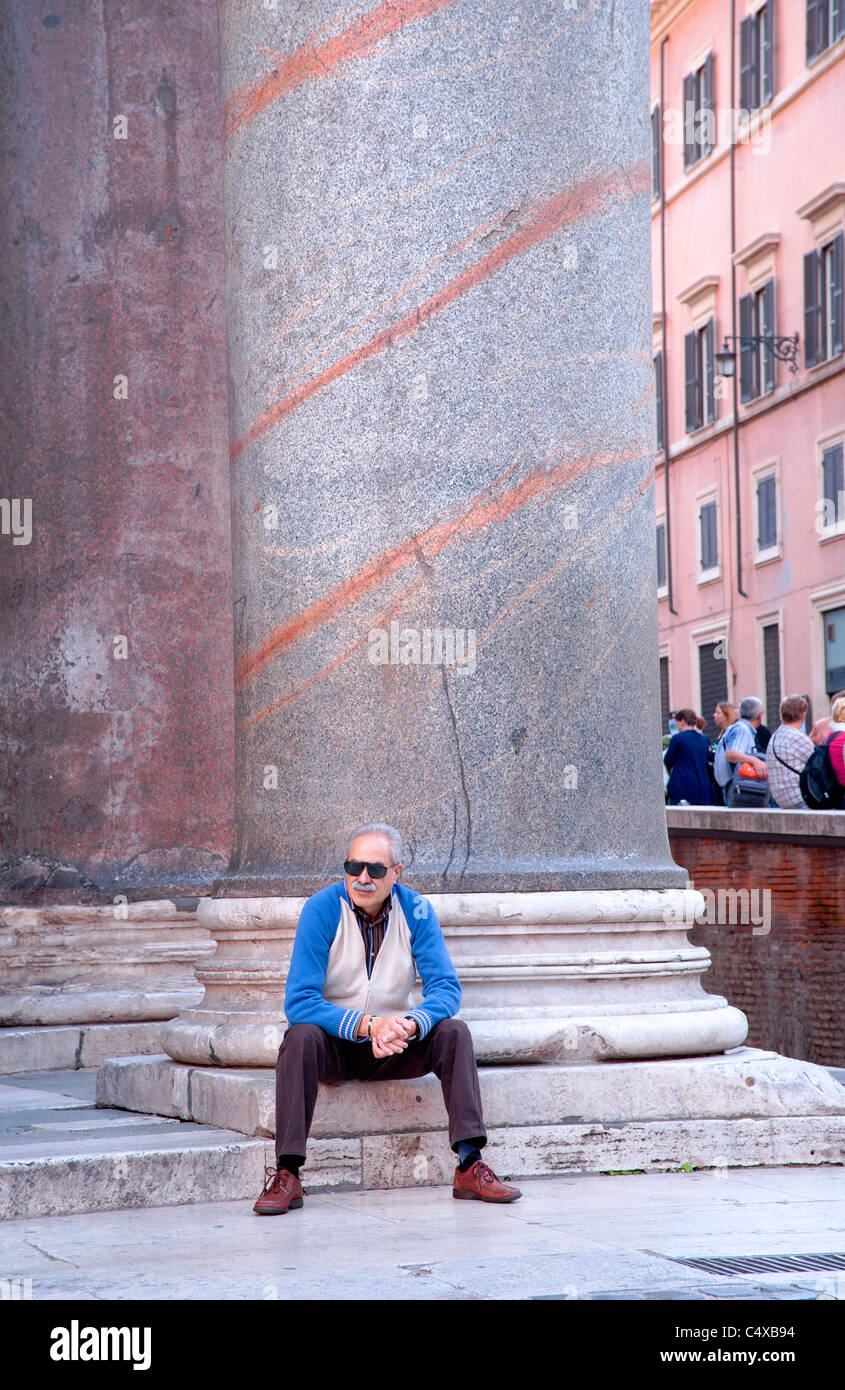 Uomo seduto su una base a colonna del Pantheon portico in Roma. Foto Stock