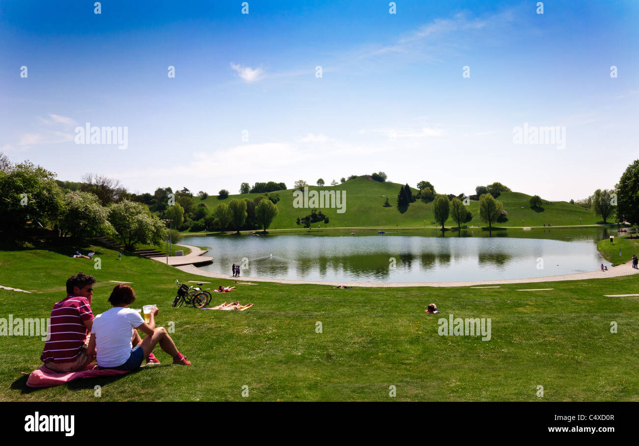 Un giovane gode di una birra sul prato all'Olympiapark - Monaco di Baviera, Germania Foto Stock