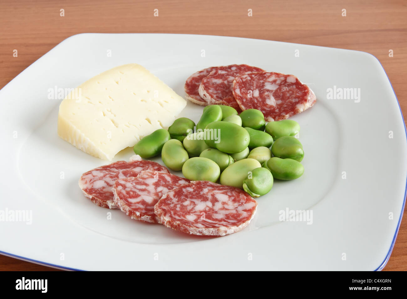 Fave con pecorino e fette di salame su una piastra bianca Foto stock - Alamy