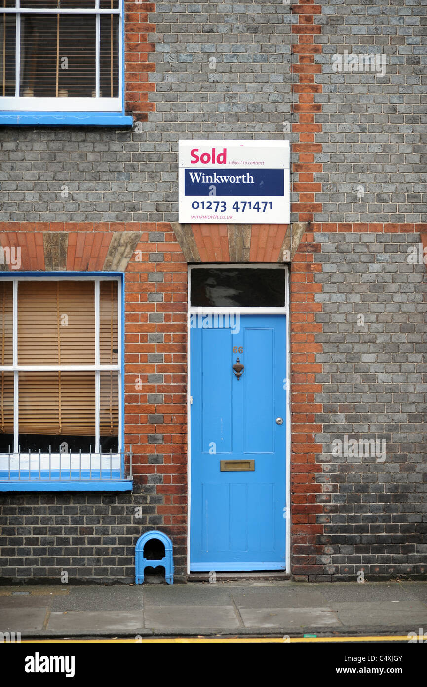 Casa con una porta blu e un agente immobiliare venduta segno sopra in East Sussex città di Lewes Regno Unito Foto Stock