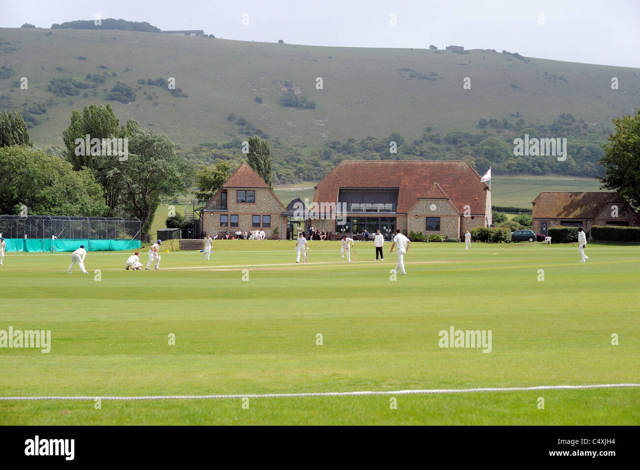 Preston nomadi giocare agli host di Horsham di cricket a loro pittoresca massa nel Sussex Fulking che è dominato da Downs Foto Stock