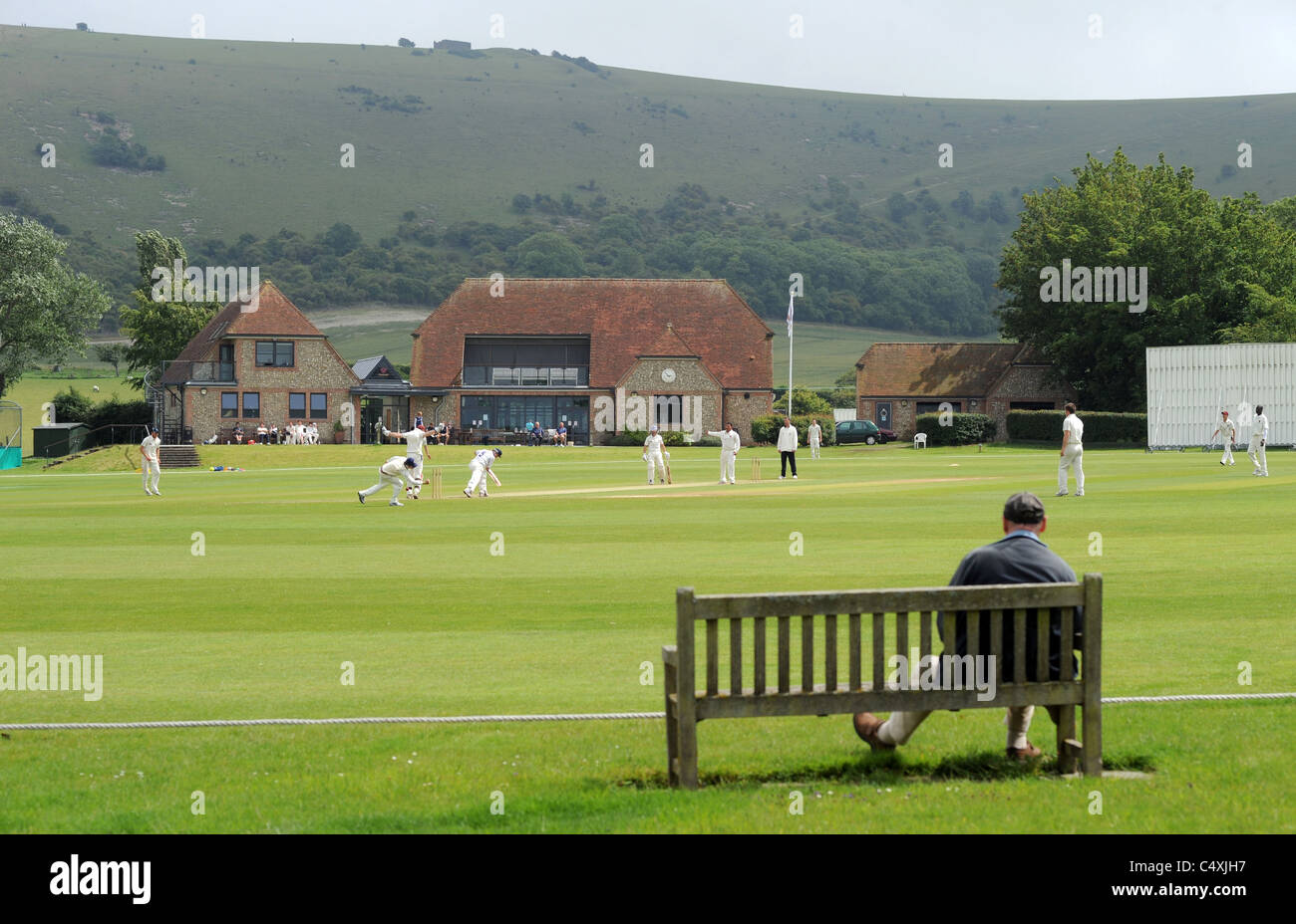 Preston nomadi giocare agli host di Horsham di cricket a loro pittoresca massa nel Sussex Fulking che è dominato da Downs Foto Stock