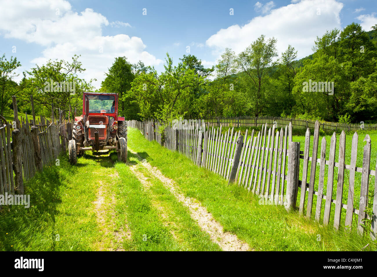 Il vecchio trattore rosso in campagna su una strada rurale Foto Stock