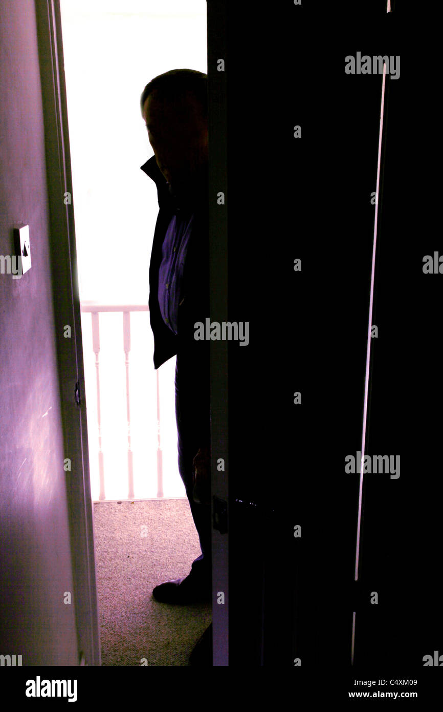Silhouette di un uomo in piedi al di fuori di una stanza buia in Cerca in. Foto Stock