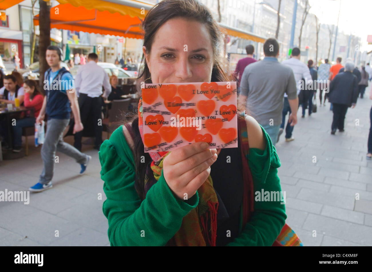 Donna nella sua 20s con una cartolina a dire ti amo Mariahilfer Strasse, la via principale dello shopping a Vienna Austria Europa centrale Foto Stock