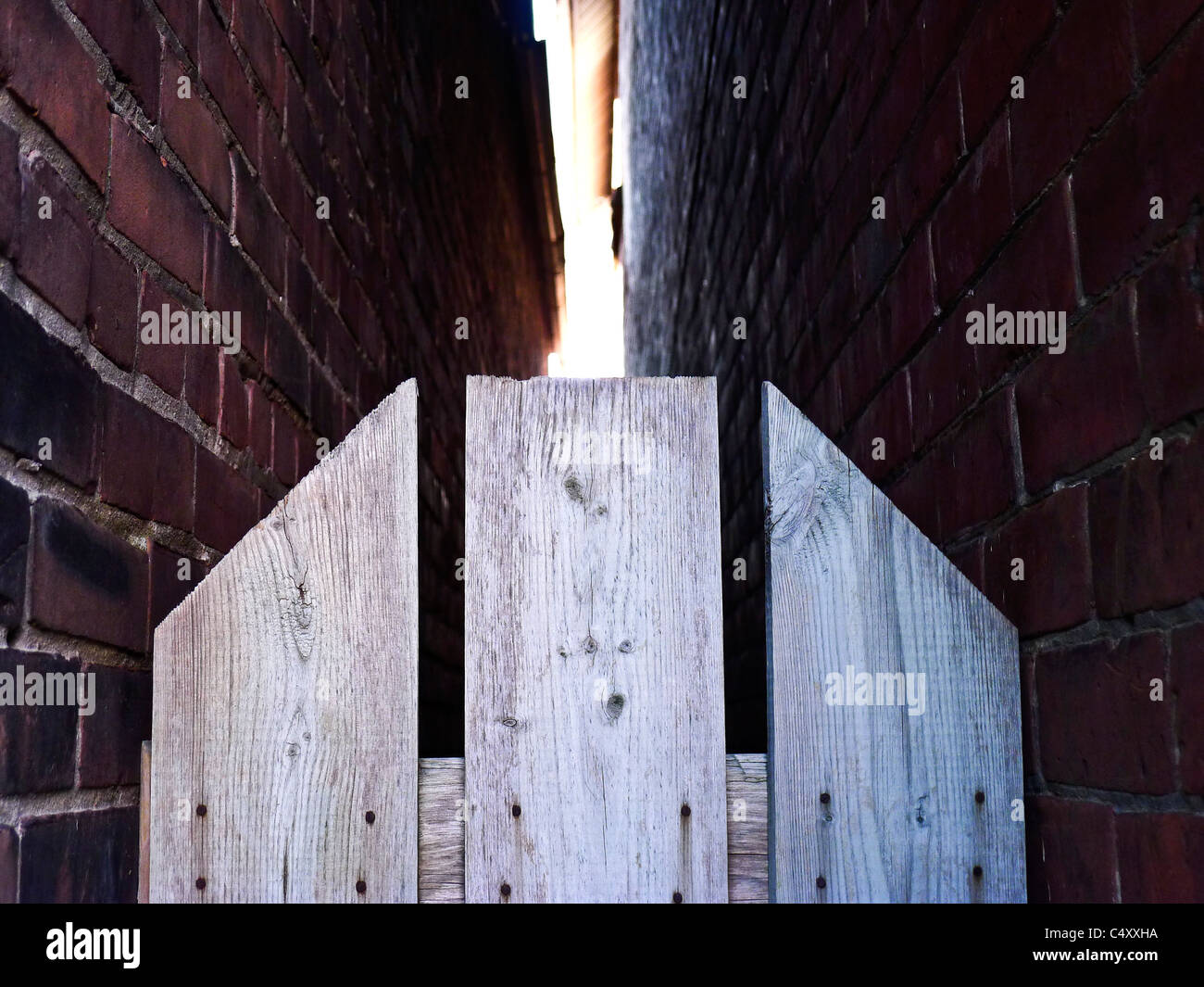Staccionata in legno la divisione di due muri di mattoni. Foto Stock