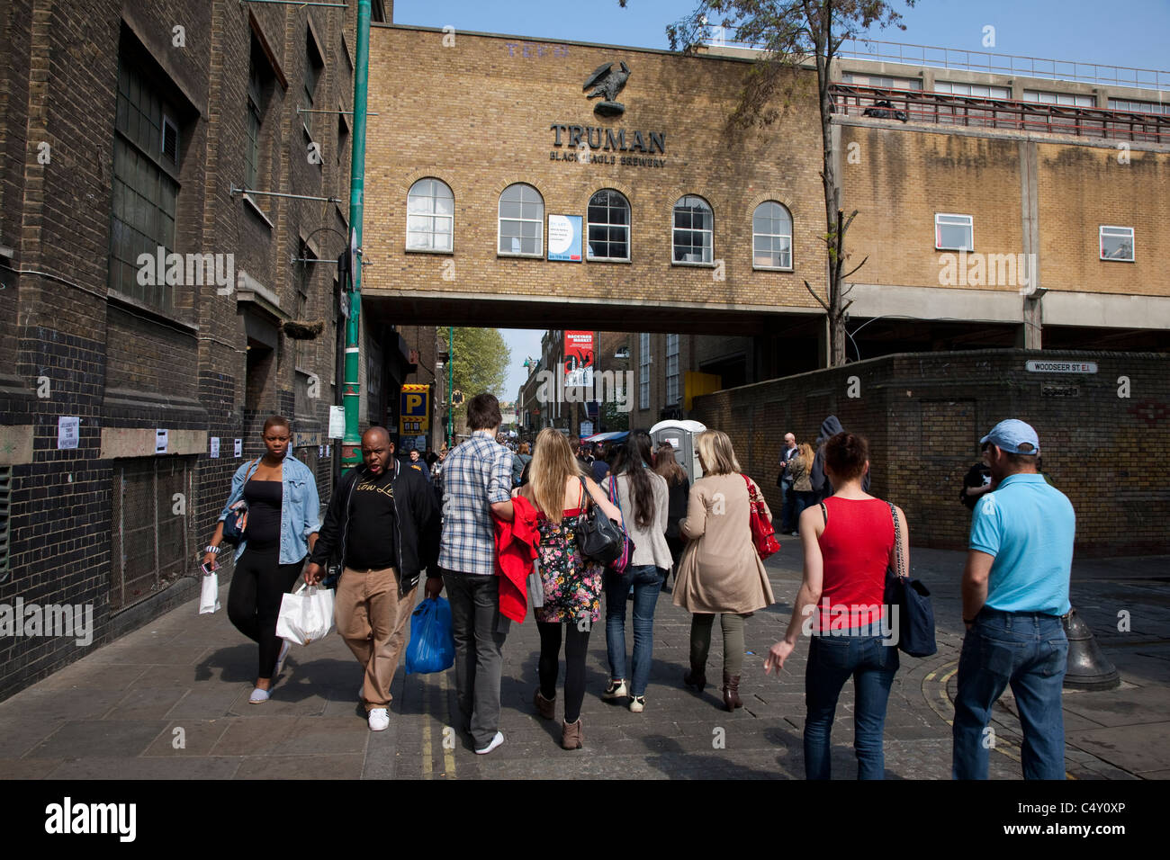 People shopping in strada dei mercati al di fuori del Vecchio Truman Brewery in Brick Lane, London, England, Regno Unito Foto Stock