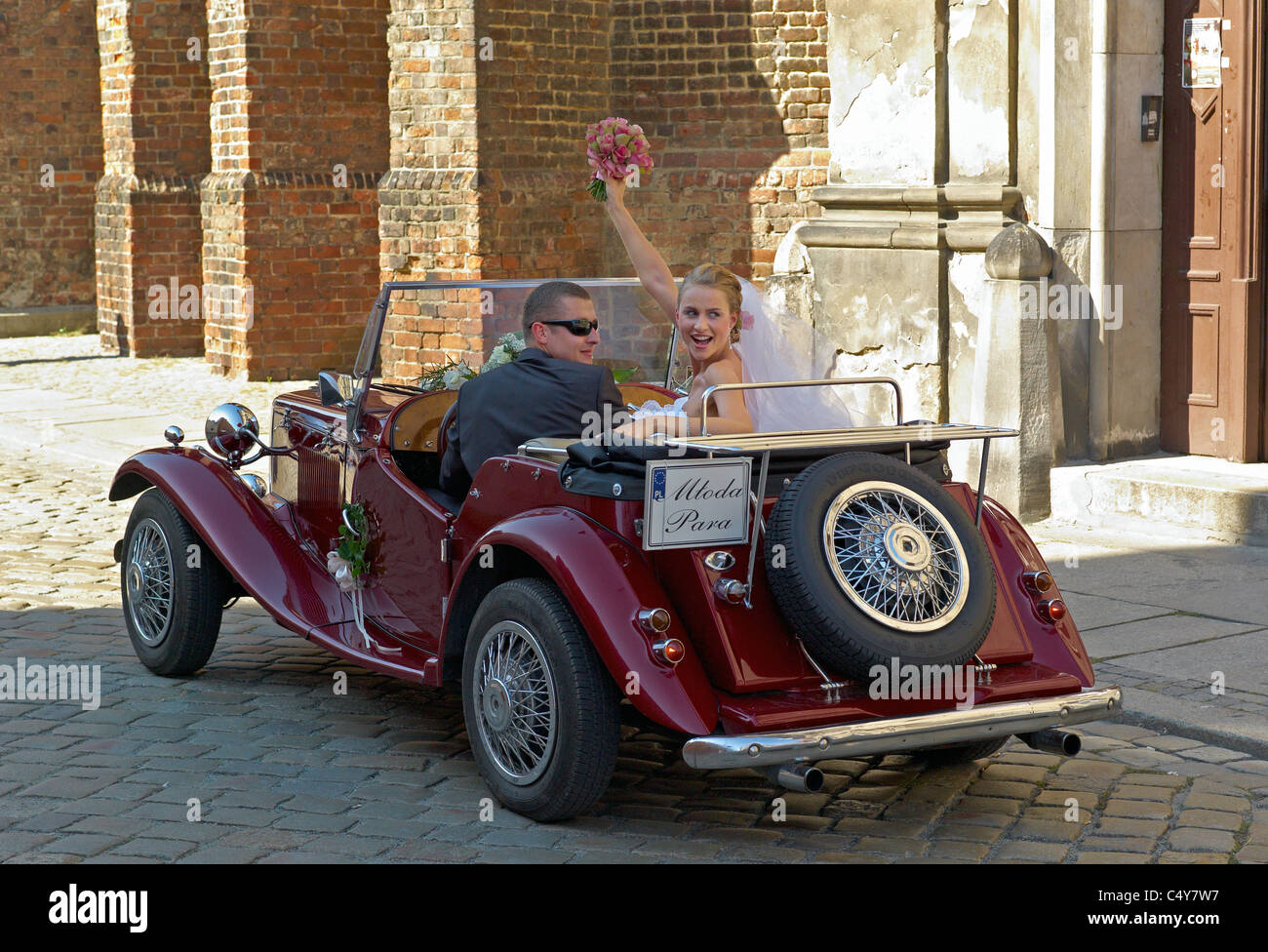 Una coppia di sposi e amici con un MG oldtimer sul Duomo Isola, Wroclaw, Polonia Foto Stock