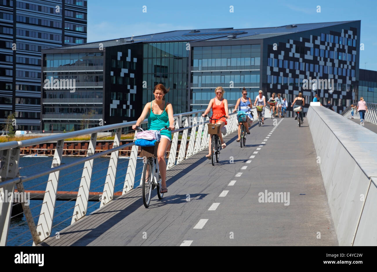 Giovani ciclisti femmina passante 190 m di lunghezza e 5,5 m di larghezza per biciclette e pedoni ponte in acciaio sopra il porto di Copenhagen, Danimarca. Foto Stock