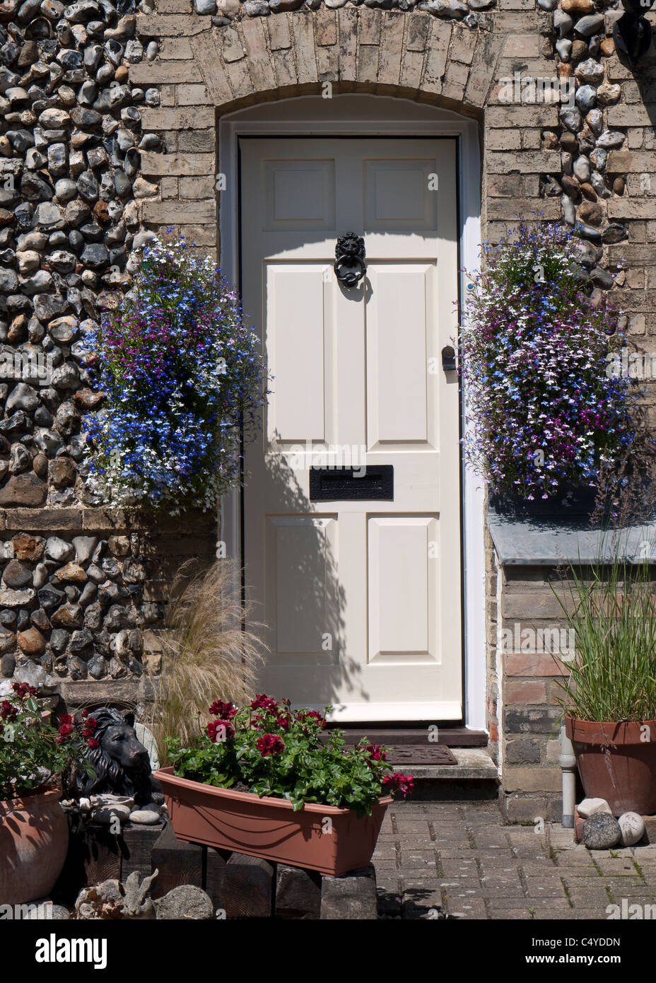 Porta del cottage in pietra con estate nei cestini appesi, Inghilterra Foto Stock