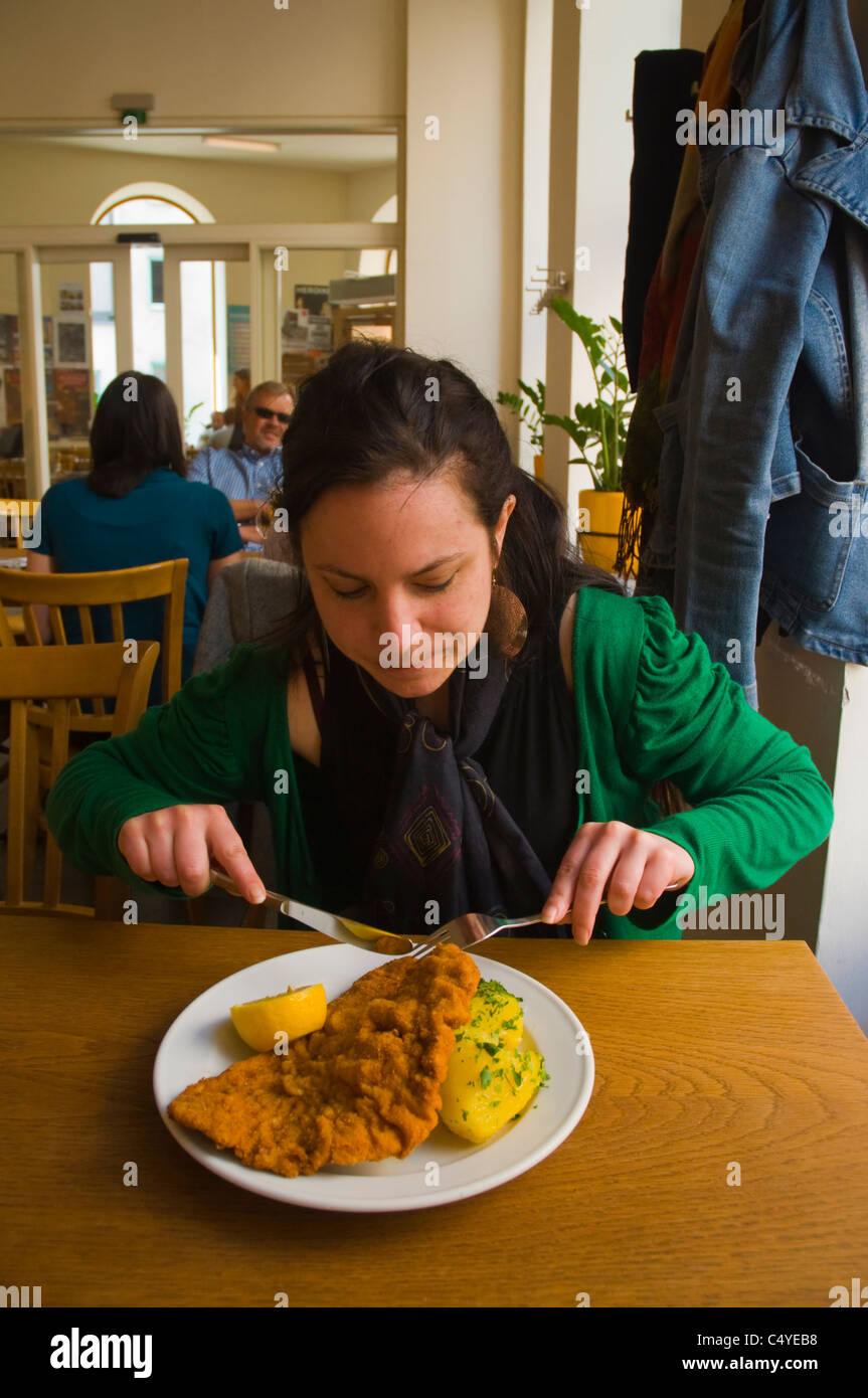 Donna nella sua 20s avente Wiener Schnitzel il fritto scaloppine in Schöne Perle ristorante interno Leopoldstadt di Vienna Foto Stock