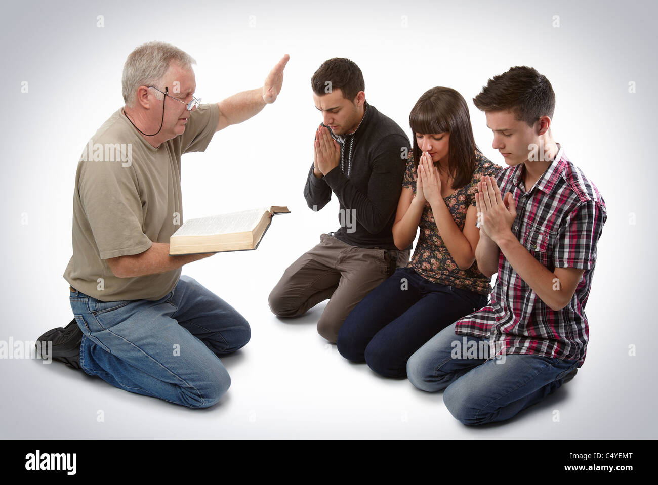 Predicatore che portano tre giovani anime in preghiera per ricevere Gesù Foto Stock