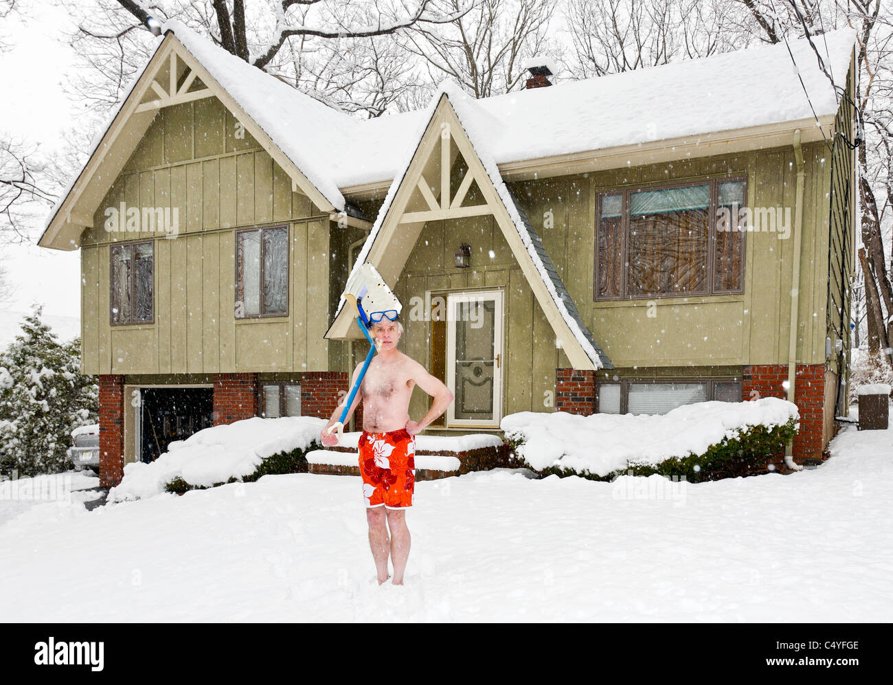 Uomo in costume da bagno in piedi di fronte alla sua casa durante una tempesta di neve. Foto Stock