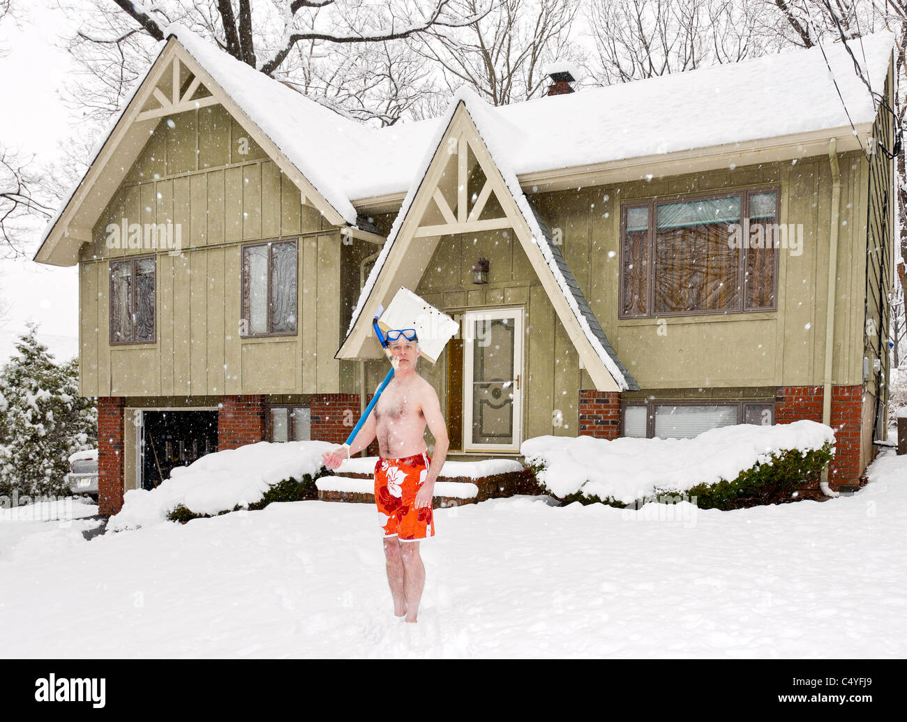 Uomo in costume da bagno in piedi di fronte alla sua casa durante una tempesta di neve. Foto Stock