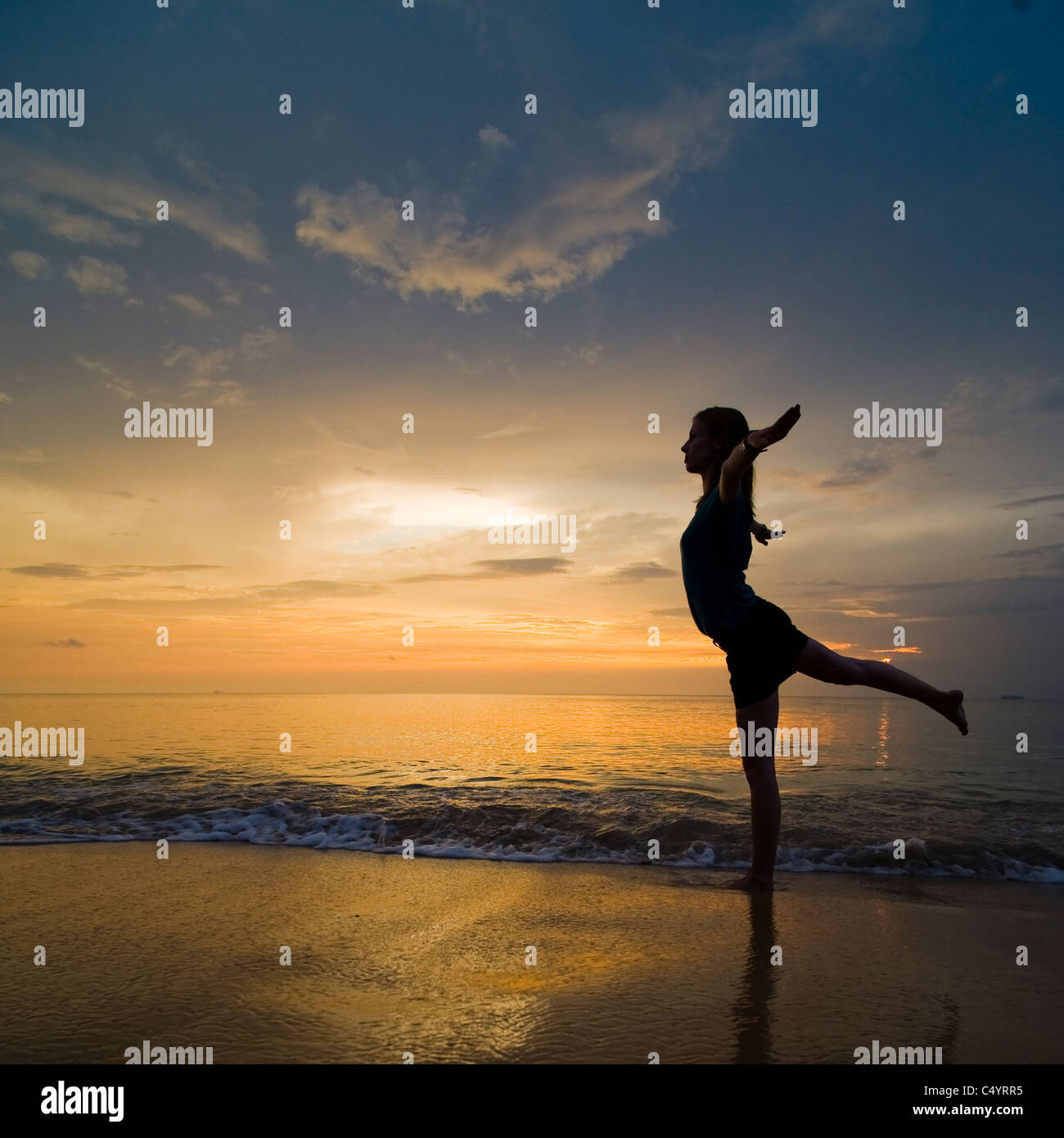 Una giovane donna facendo esercizi yoga sulla spiaggia al tramonto.Preso in Phra Ae Beach (Long Beach), Koh Lanta (Lanta Island),Thailandia Foto Stock