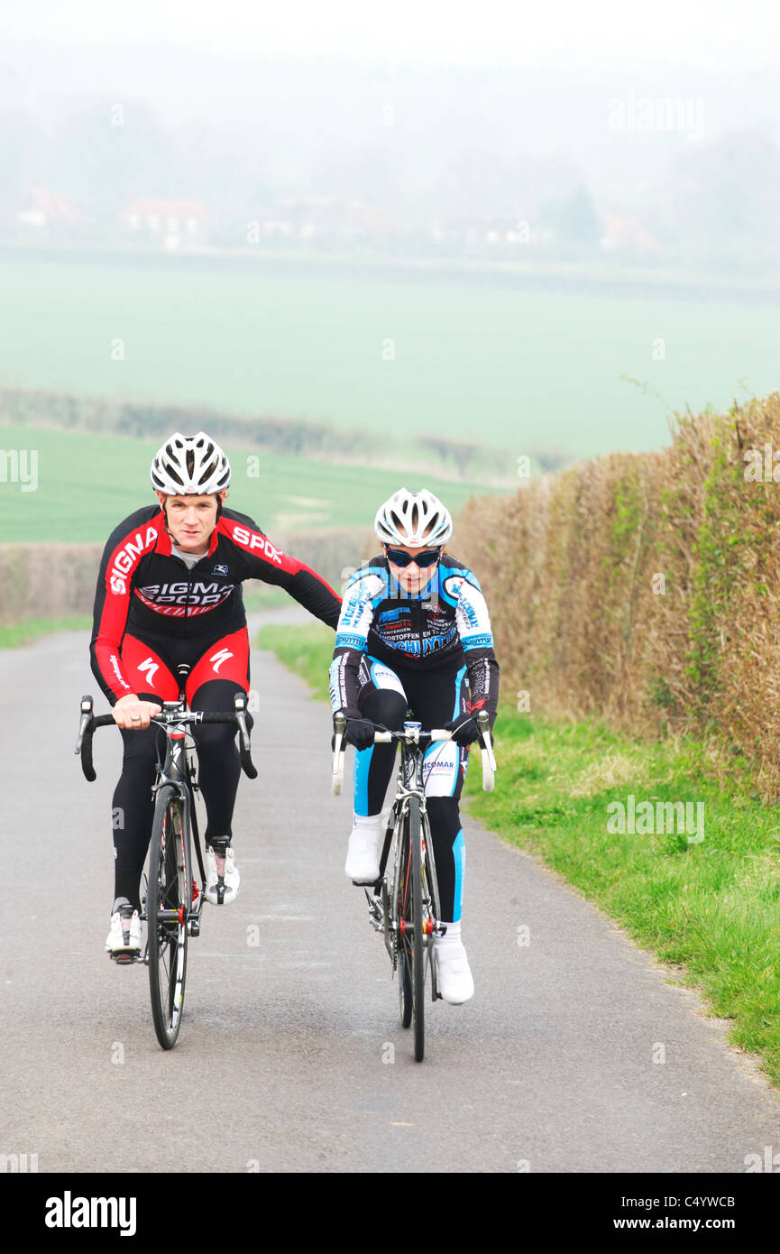 La formazione della corsa di una UK pro cycling team, sigma sport aiutando un pilota femmina fino alla cima di una collina Foto Stock