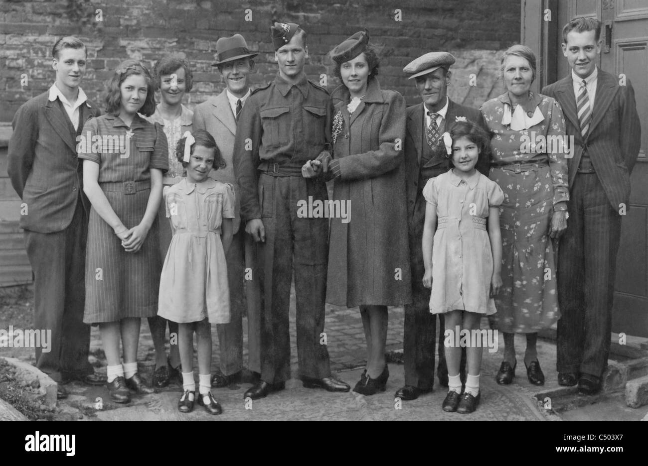 Un soldato nel Queens reggimento in congedo durante la seconda guerra mondiale si sposano e pone orgogliosamente con la famiglia. Foto Stock