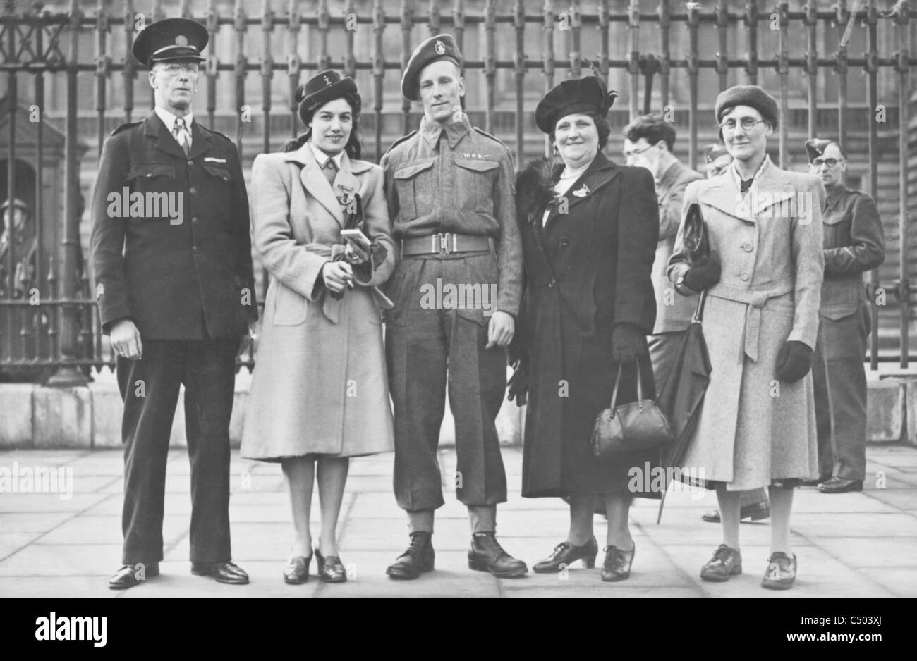 Un soldato dalla seconda guerra mondiale riceve una medaglia militare sorge fuori dai cancelli a Buckingham Palace con la sua famiglia. Foto Stock