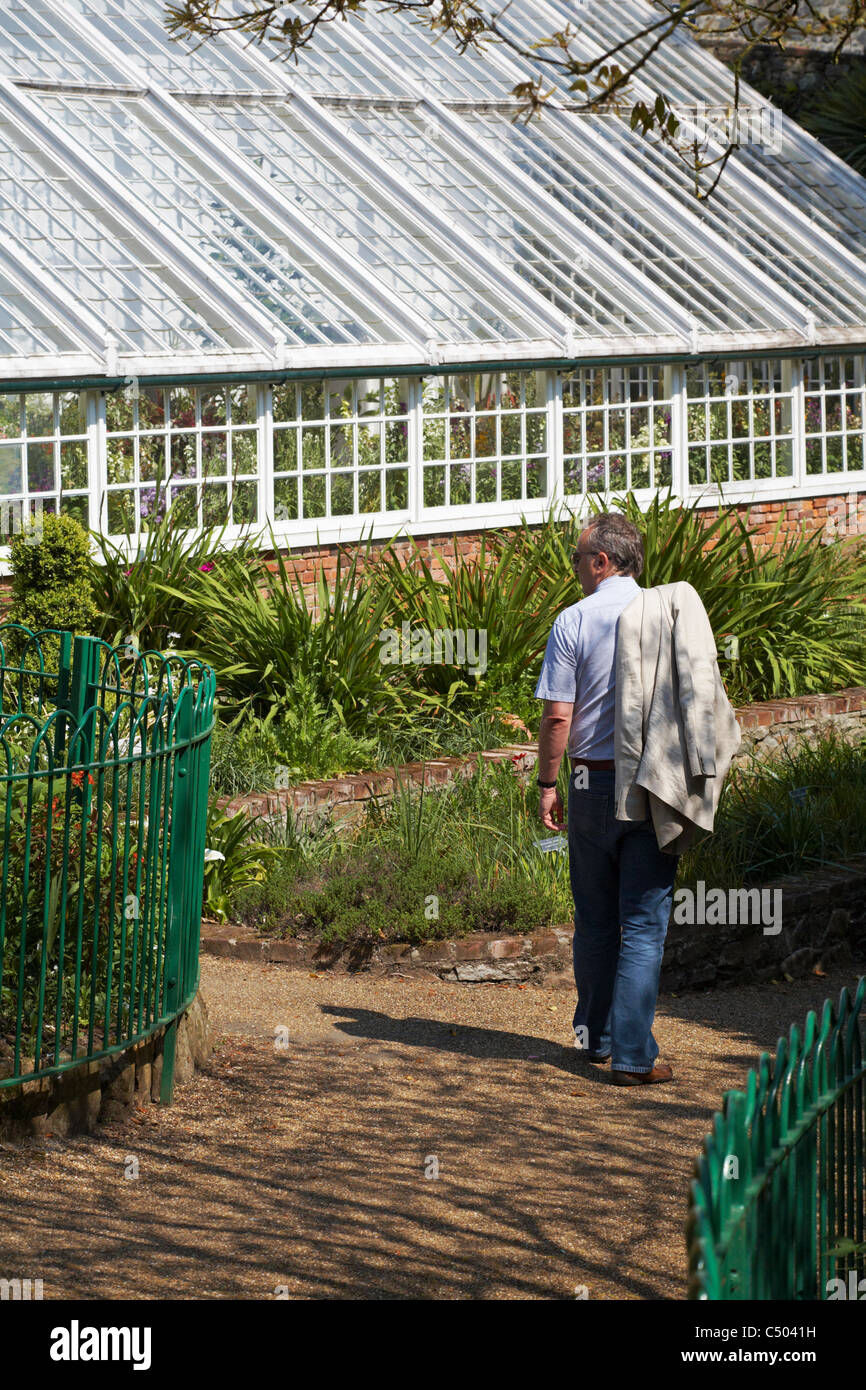 Uomo che cammina attraverso Candie Gardens verso la serra St Peter Port Guernsey, nel mese di aprile Foto Stock
