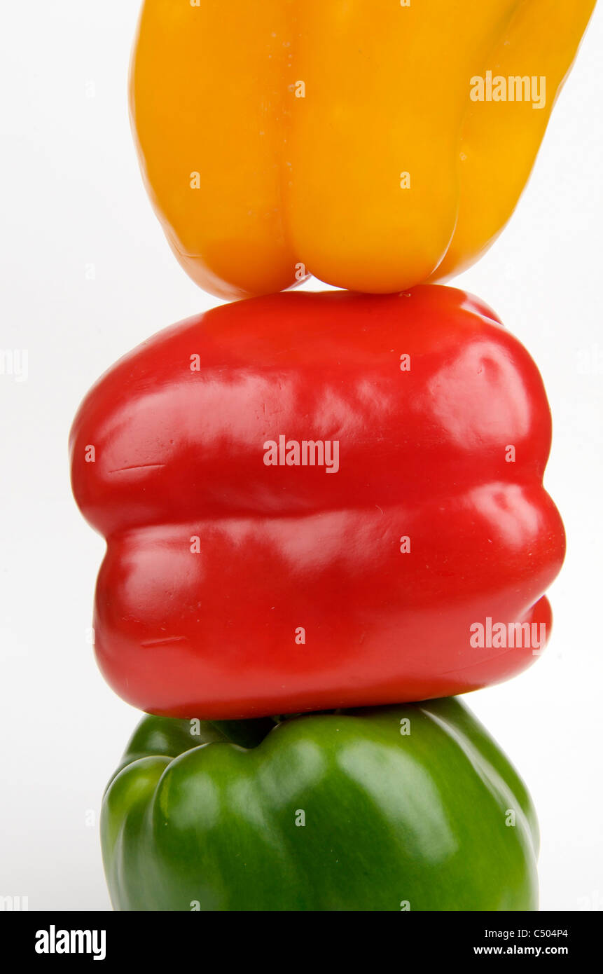 Peperoni colorati impilati creativamente su uno sfondo bianco, con vivaci sfumature per l'ispirazione culinaria e una sana alimentazione Foto Stock