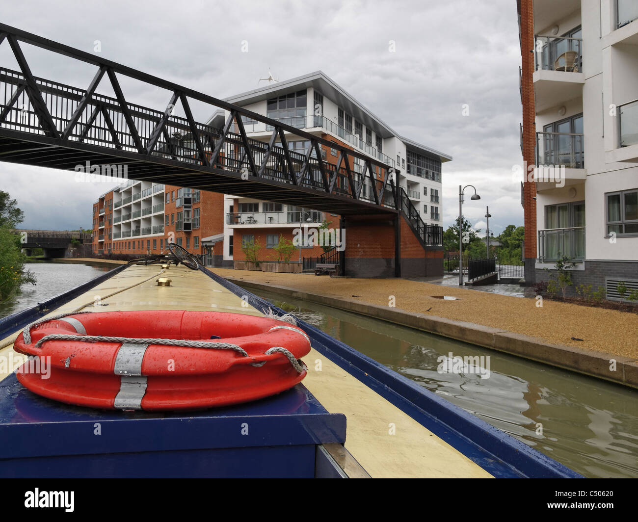 Una barca stretta passando attraverso un paesaggio urbano sul Grand Union Canal at Wolverton, Buckinghamshire, Inghilterra. Foto Stock