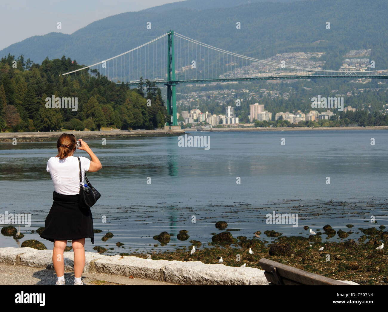 Una donna di fotografare la Porta del Leone Bridge da Stanley Park, Vancouver, Canada Foto Stock