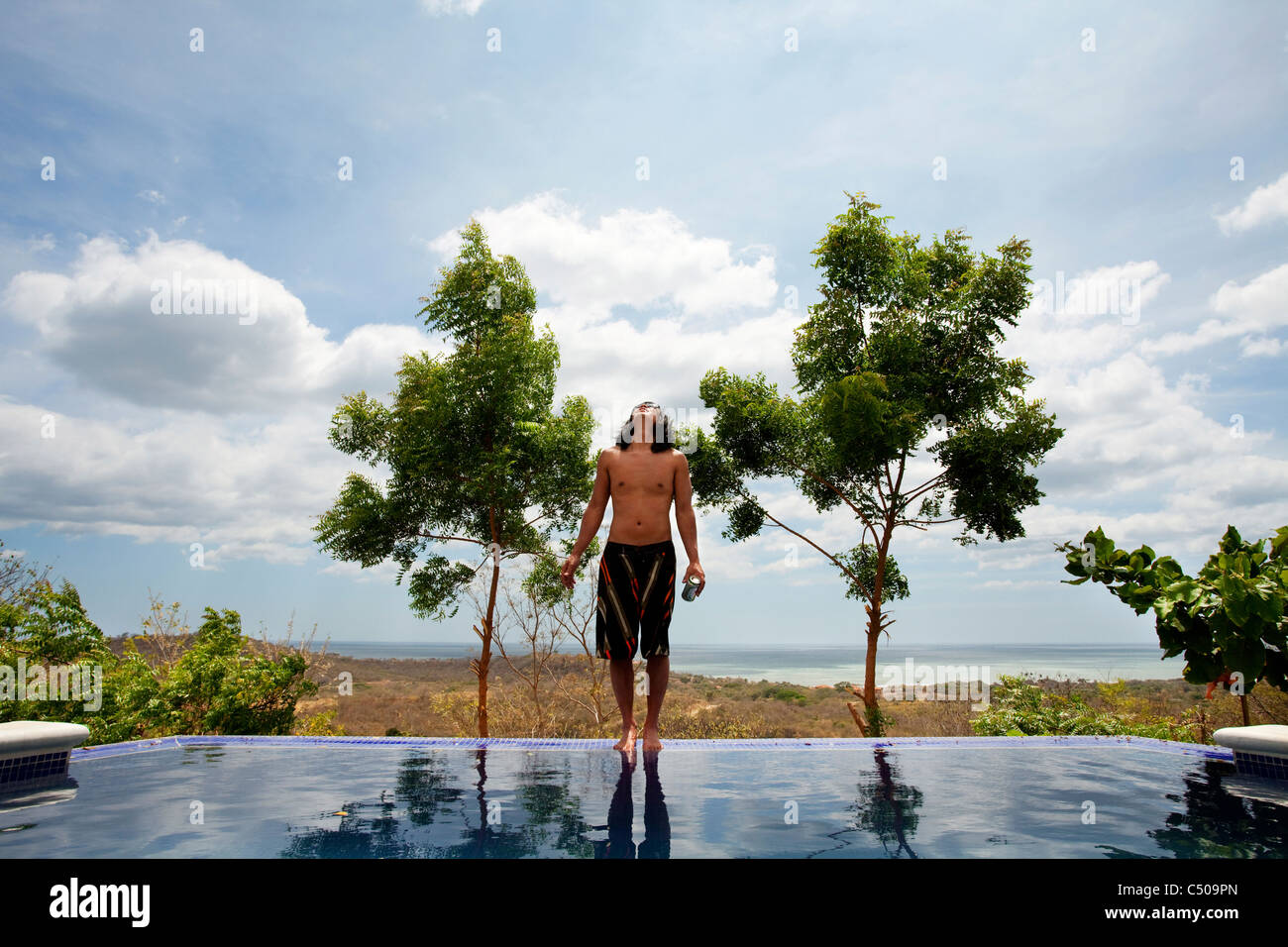 Uomo asiatico in piedi sul bordo della piscina infinity Foto Stock