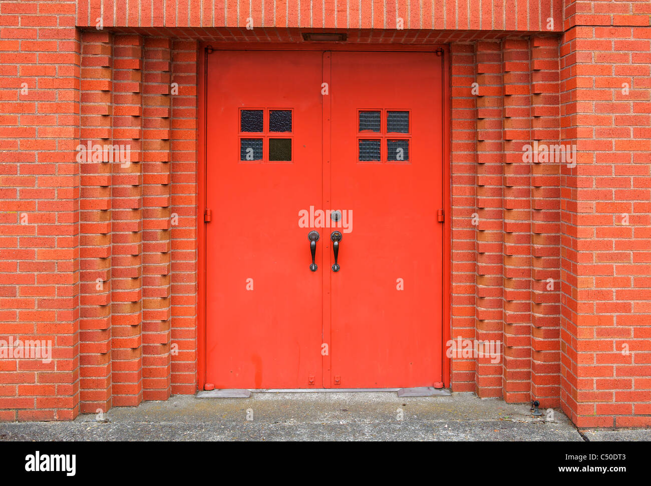 Rosso di due porte di metallo incassate nel muro di mattoni della chiesa Foto Stock