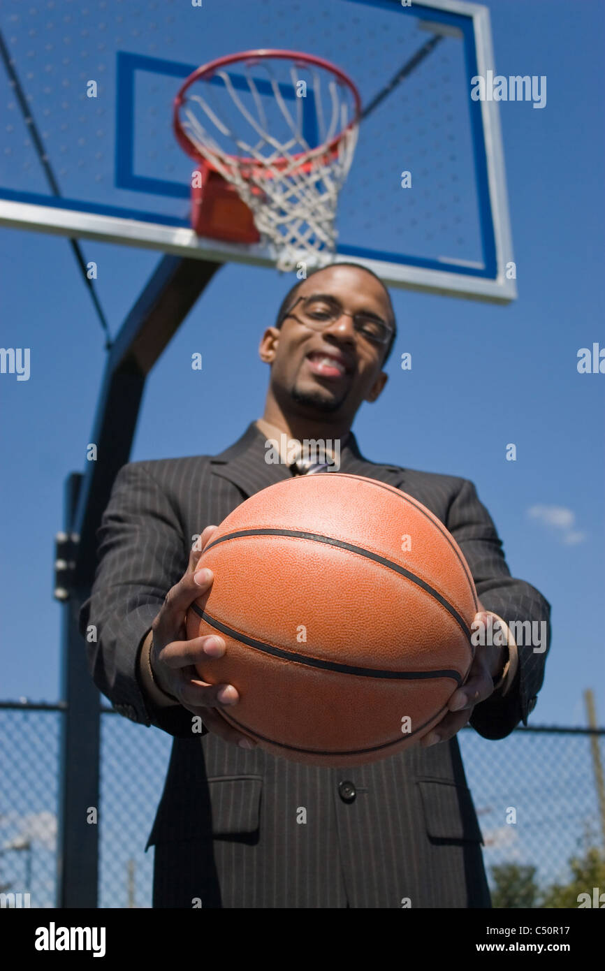 Un giovane uomo in un business suit all'esterno vuoto pallacanestro. Foto Stock