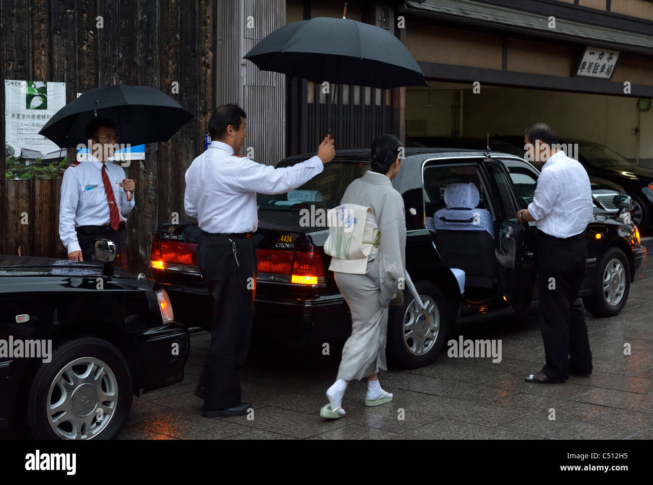 Un giapponese Geisha (Geiko) a piedi ad un taxi che aspetta nello storico quartiere di Gion, Kyoto, Giappone JP Foto Stock