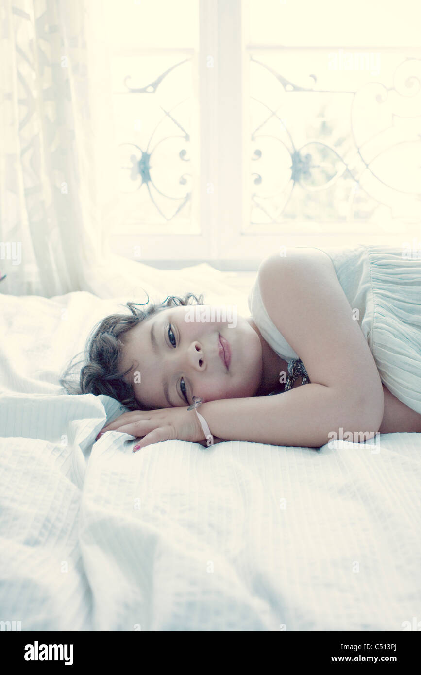 Sorridente bambina giacente sul letto Foto Stock