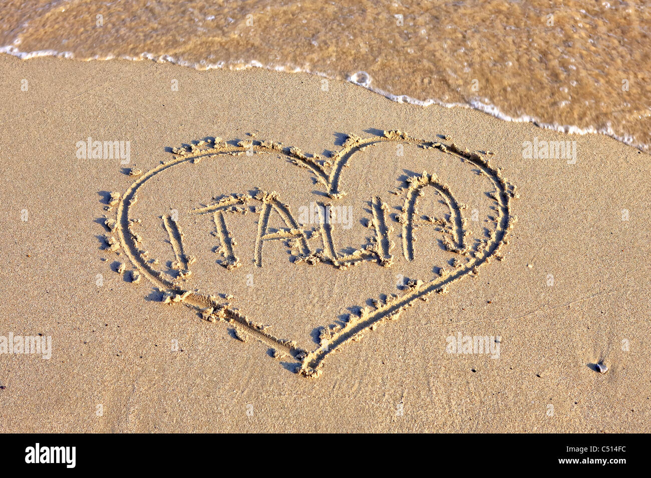 Un cuore in spiaggia di sabbia con scrittura Italia Foto Stock