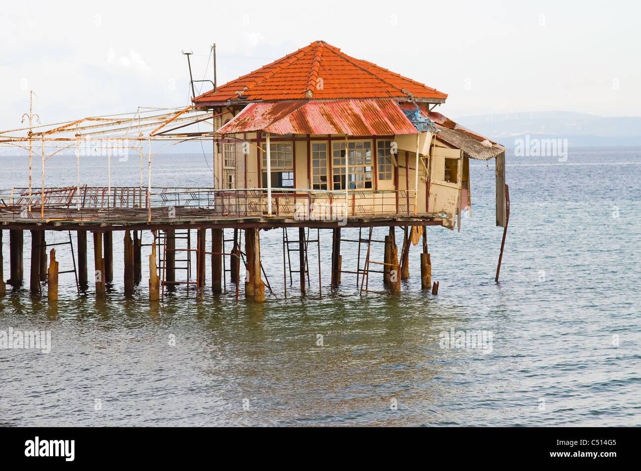 Un molo abbandonato con un edificio rovinato sul suo bordo, in Edipsos, Grecia Foto Stock
