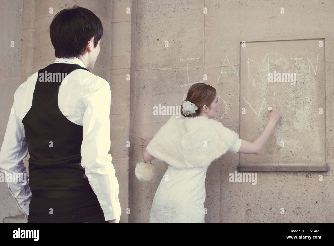 Sposa scrivendo 'Io sono innamorato' sulla parete, sposo guardando Foto Stock