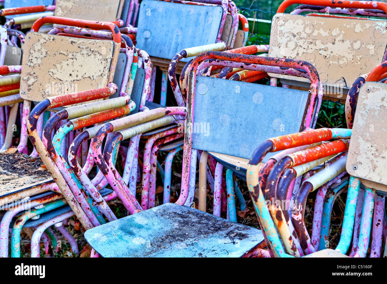 Colorati e vecchio arrugginito sedie impilate Foto Stock