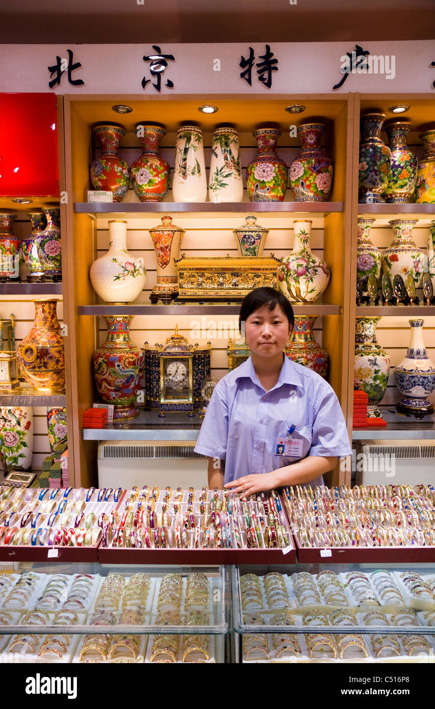 Donna adulta / femmina / girl shop assistant con il display e il contatore. La Cloisonne regali nel Palazzo Estivo di Beijing in Cina. Foto Stock