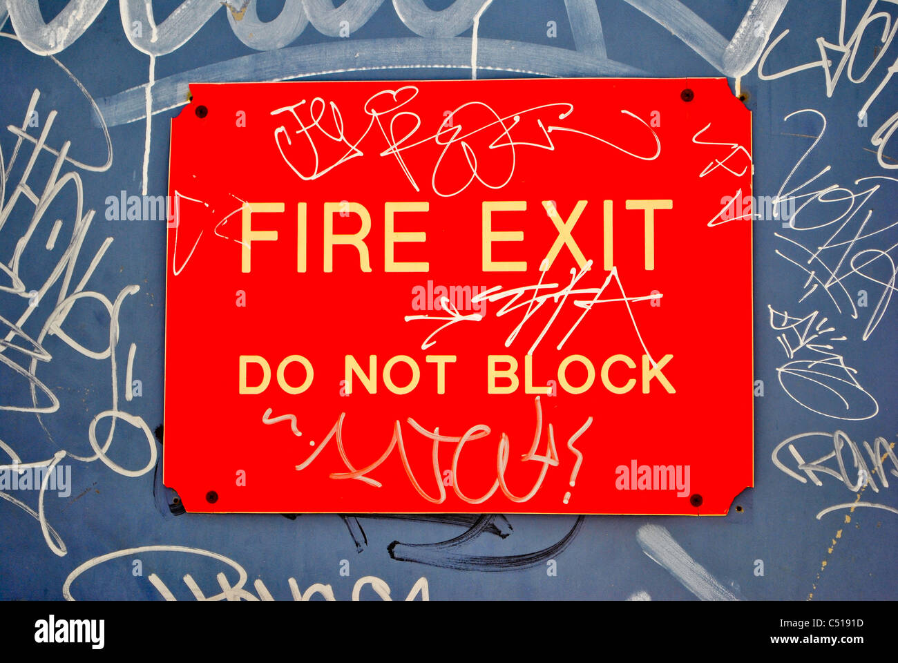 Cartello stradale (fire exit, non bloccare) con graffiti su di esso. Foto Stock