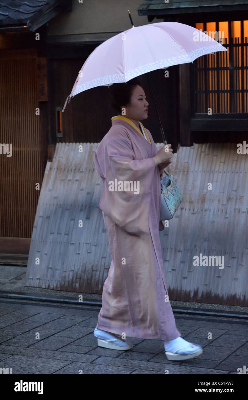 Una Geisha Giapponese (Geiko) che cammina lungo i ristoranti tradizionali nello storico quartiere di Gion, Kyoto, Giappone JP Foto Stock