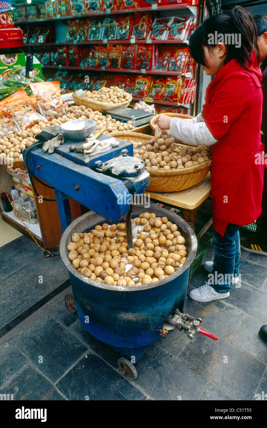 Donna preparando le noci in vendita in un mercato, Citta' di Xian, Shaanxi, Cina Foto Stock