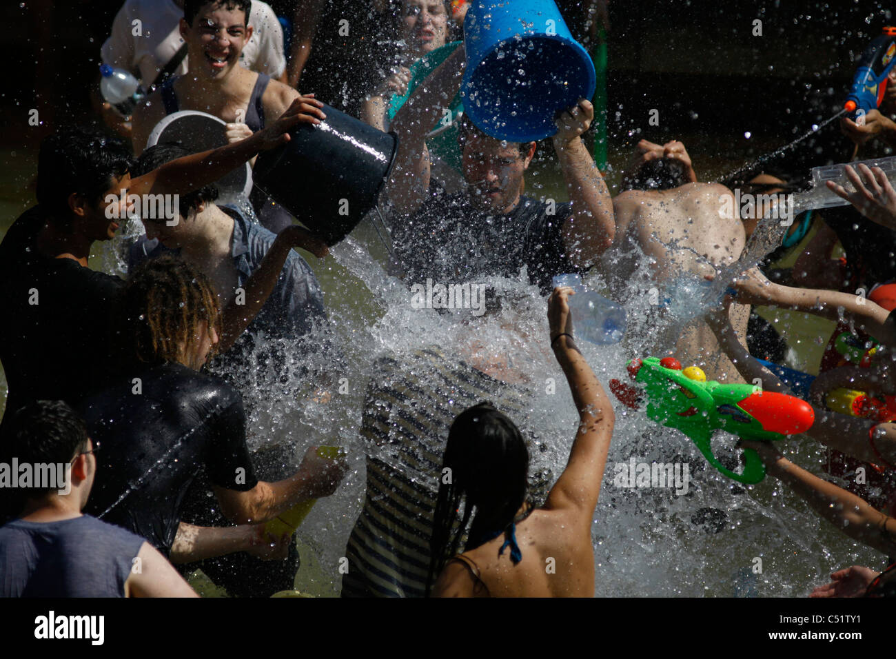 Giovani gaudenti ebraica spry acqua su ogni altro durante l'acqua annuale lotta in Rabin Square nel centro cittadino di Tel Aviv Israele Foto Stock