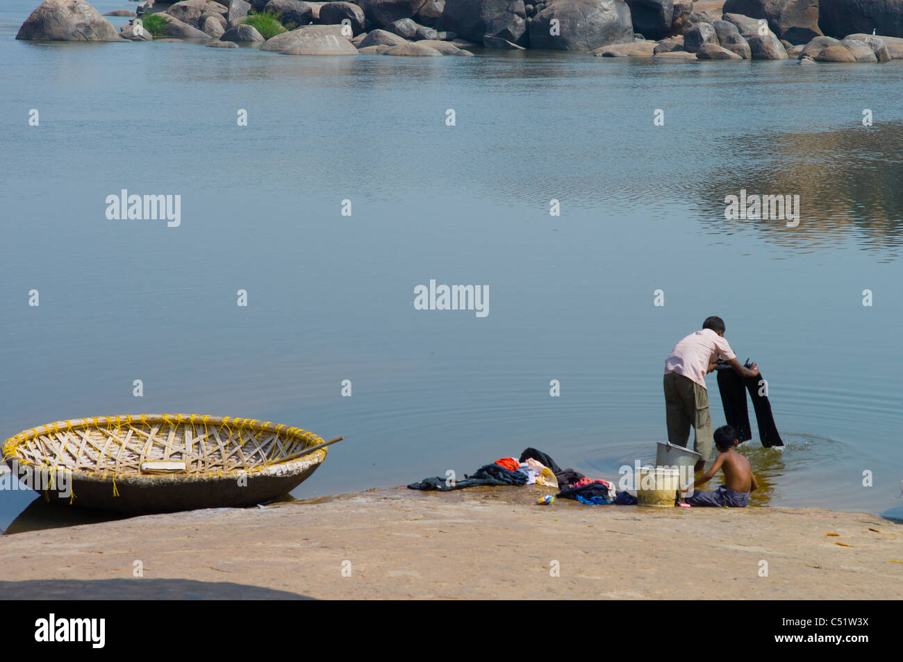 Un uomo a lavare i panni nel fiume Tungabhadra in Hampi, nello stato di Karnataka, Insia. Foto Stock