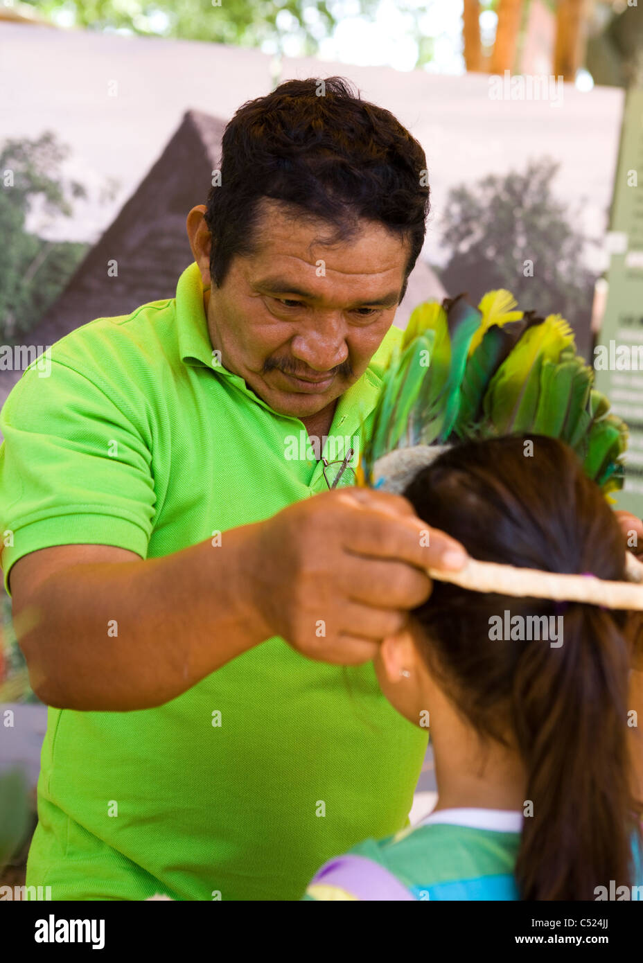 Un colombiano nativo uomo mette su un filetto di piuma sulla ragazza giovane Foto Stock