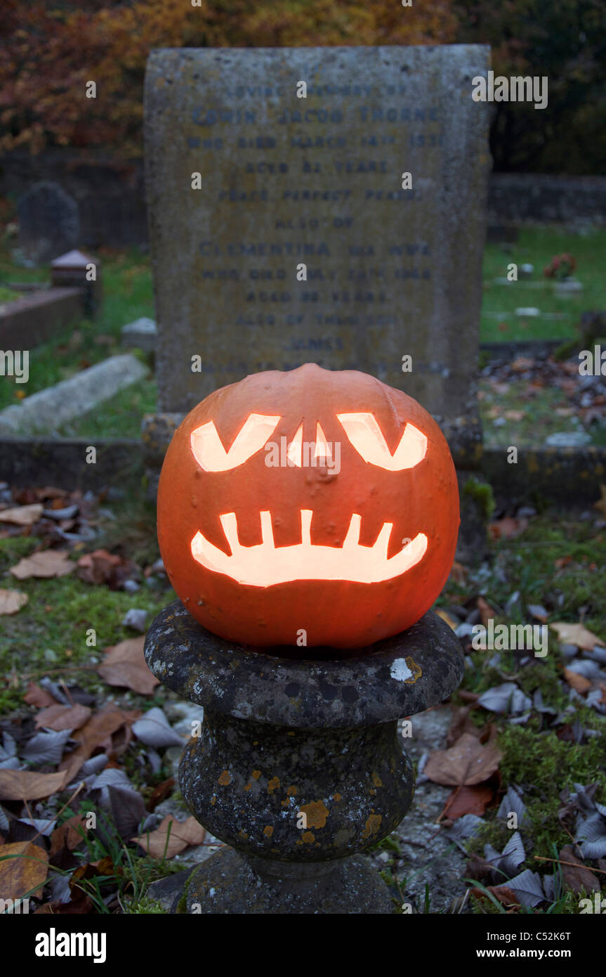 Un Halloween Jack O' Lantern intagliati da una zucca, incandescente a lume di candela in un antico cimitero. Inghilterra, Regno Unito. Foto Stock