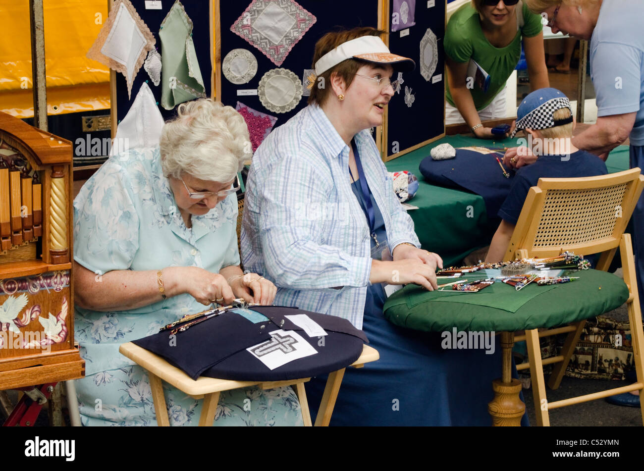 Due signore dimostrando tradizionali pizzi a St Albans street market Hertfordshire, Regno Unito Foto Stock
