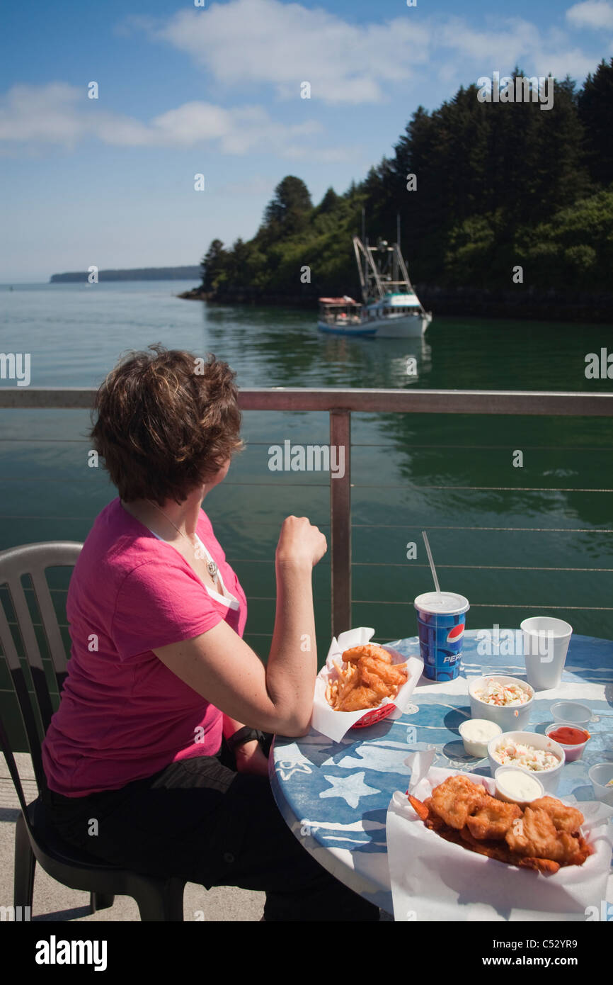 Guardare della donna e mangiare un pranzo a base di pesce presso il fianco del canale Chowder House di Kodiak, isola di Kodiak, Alaska Foto Stock